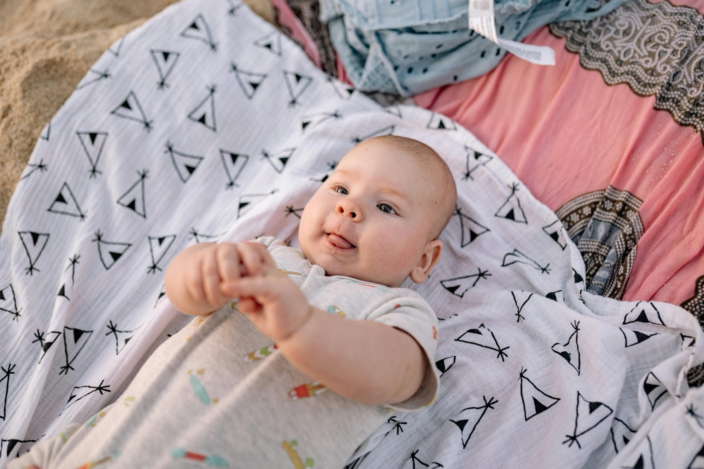 Baby lying on a blanket sticking out tongue
