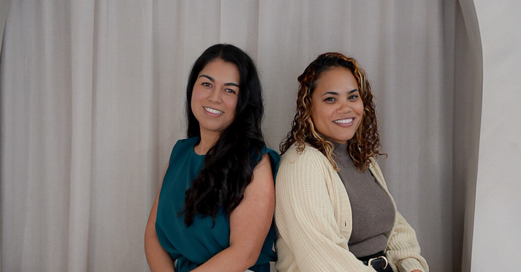 Dr. Crystal Corona and Dr. Crystal Venturino smiling, seated back to back